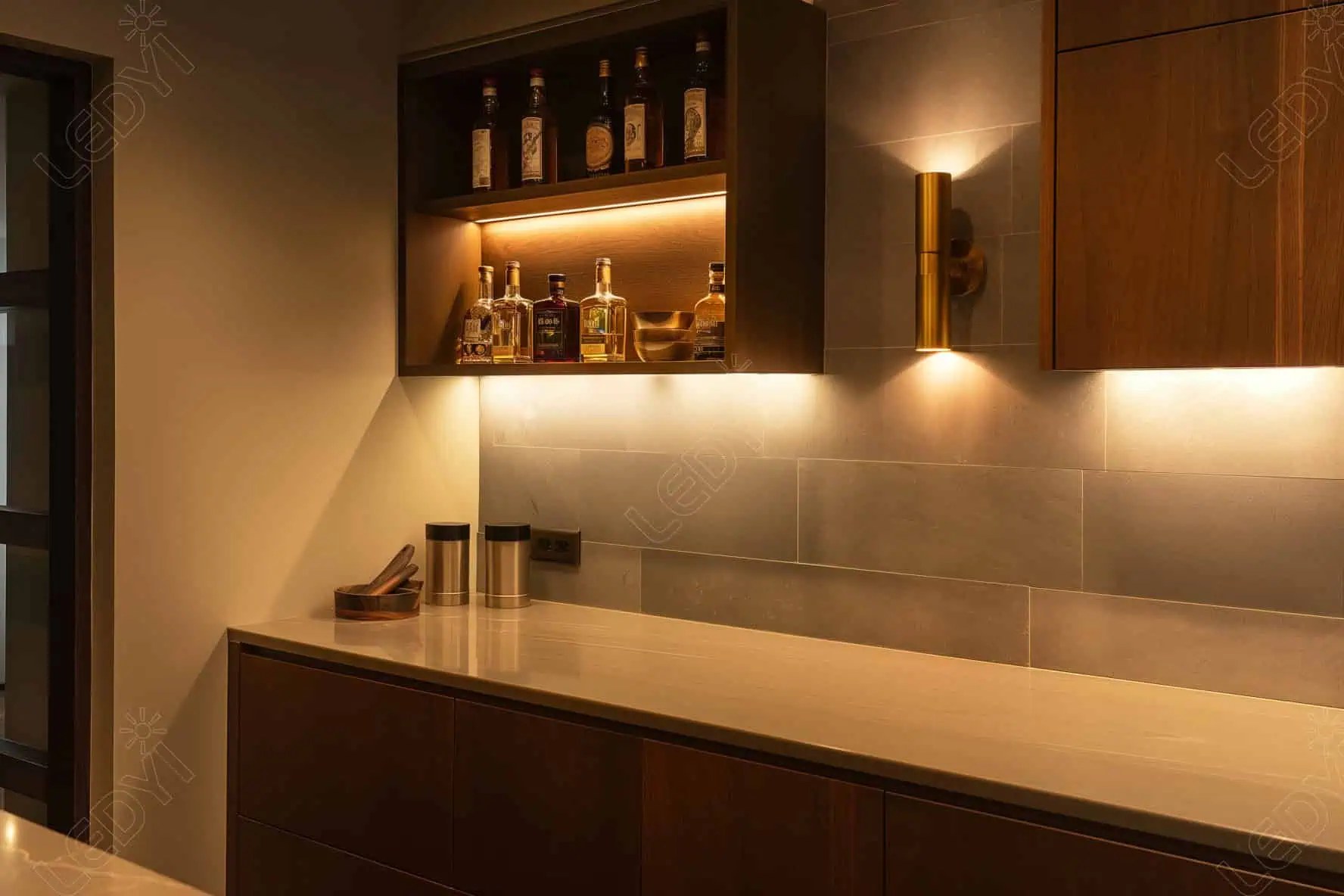 Modern kitchen with under-cabinet LED lighting and bottles.