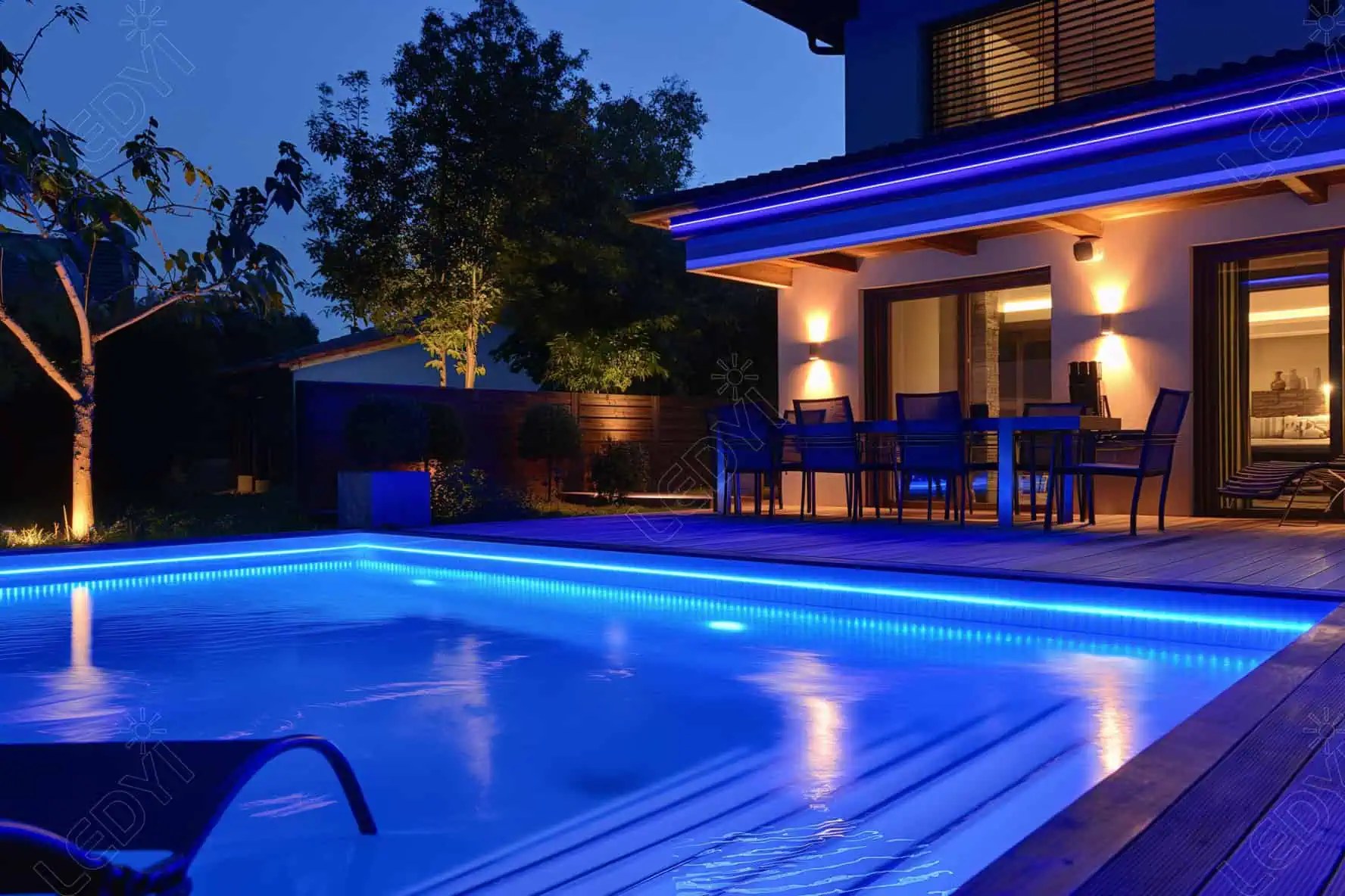 Modern backyard pool with blue LED lights at night.