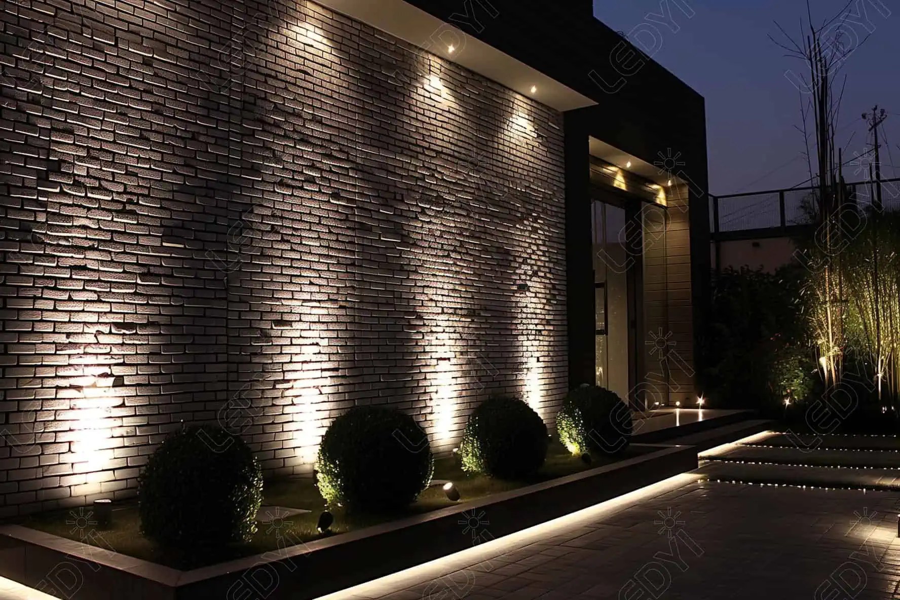 Nighttime garden with modern wall lighting.